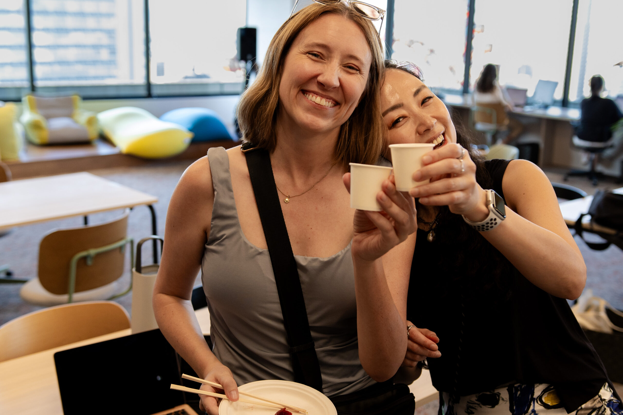 Two participants smiling and toasting with paper cups in the FUTRWORKS coworking space